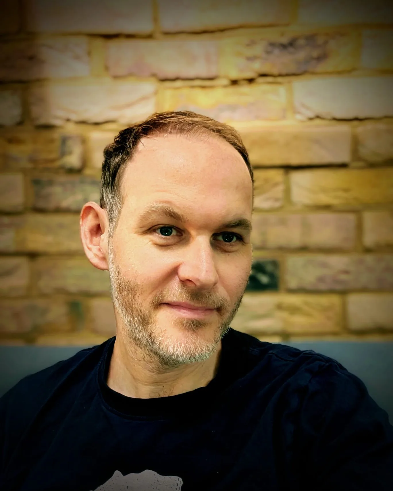 Jayson Robinson, creator of Forewords, photographed against a brick wall in London
