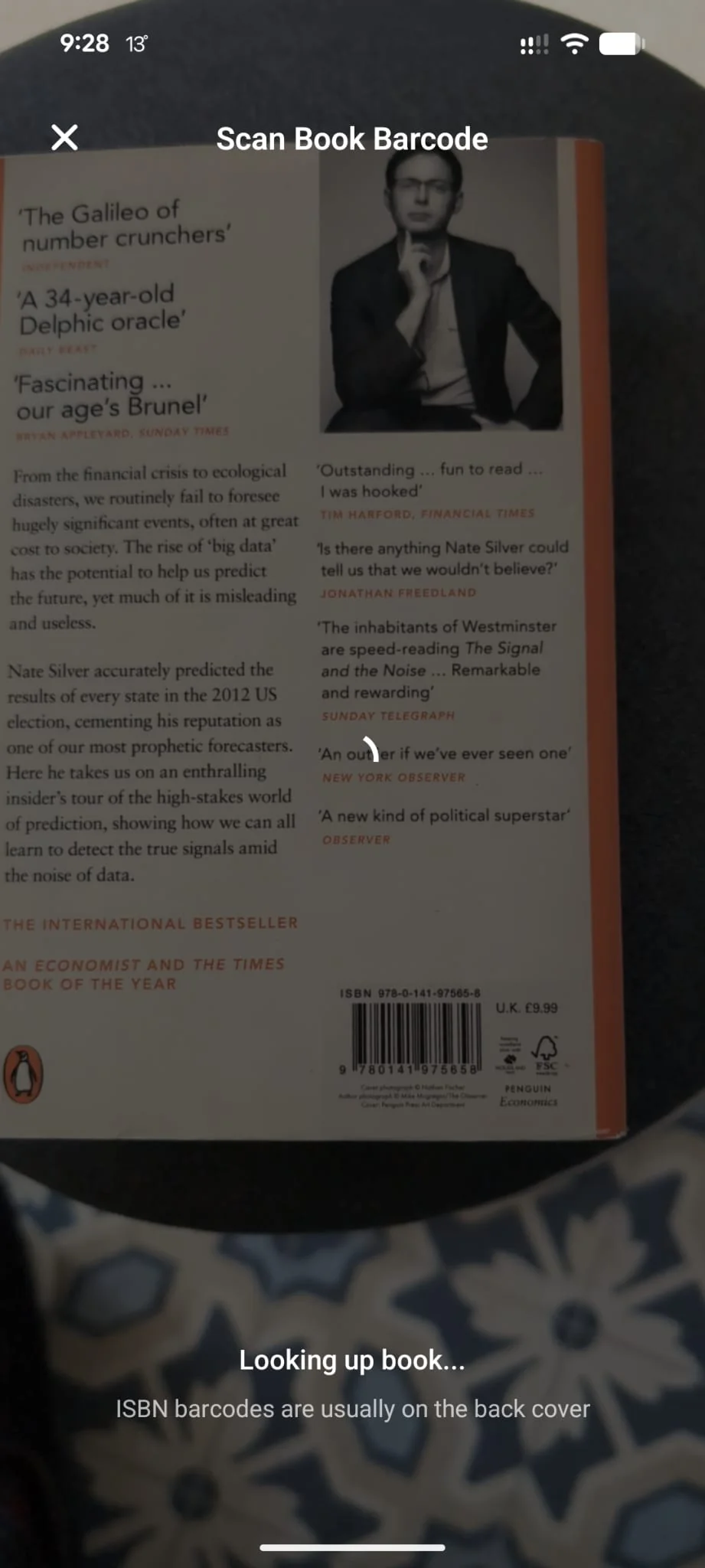 Forewords's Scan Book Barcode screen with the camera viewfinder pointed at the back cover of a Penguin paperback. The ISBN barcode is visible mid-frame, with a 'Looking up book...' status at the bottom and a hint reading 'ISBN barcodes are usually on the back cover'.